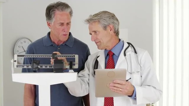 Senior doctor weighing elderly patient