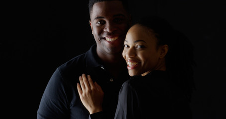 Dramatic portrait of young Black couple holding each other smiling