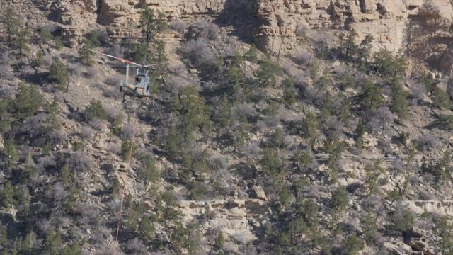 Helicopter carrying supplies decending to land in mountains