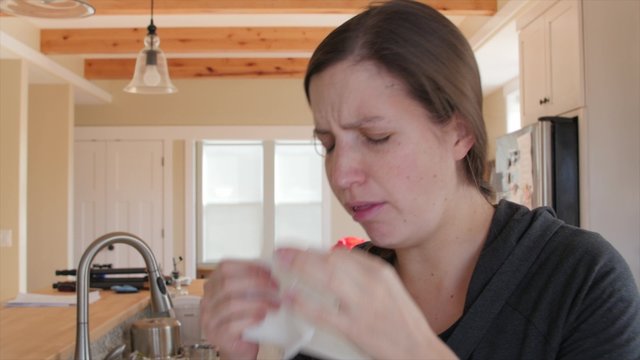 A sick woman blows nose in kleenex
