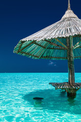 Bamboo beach umbrella in the water of tropical island