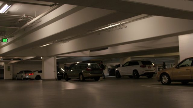 Car driving in underground parking garage with people