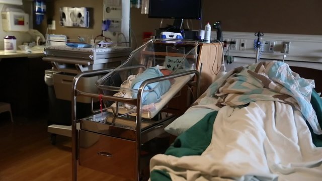 a tiny newborn sleeping by his mother in hospital dolly shot