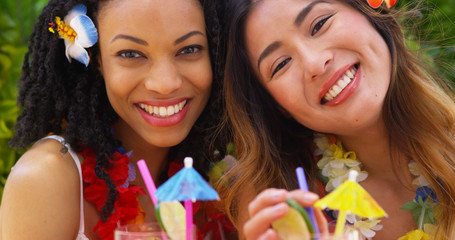 Close up of smiling women on tropical vacation sipping cocktails