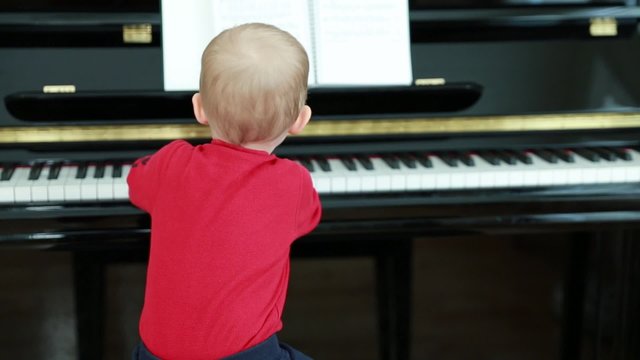 a little toddler playing on the piano