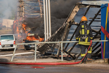 Fire fighter in the background of fire of buildings and cars