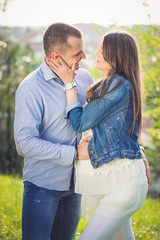 Fototapeta premium Pregnant young woman in love. Happy young couple exchange tenderness outside.