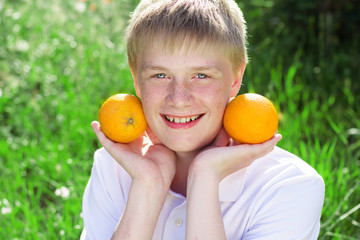 Teenager boy is holding two oranges