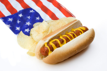 Hot Dog and Chips American Style – A hot dog with mustard, potato chips and an American flag napkin in the background.