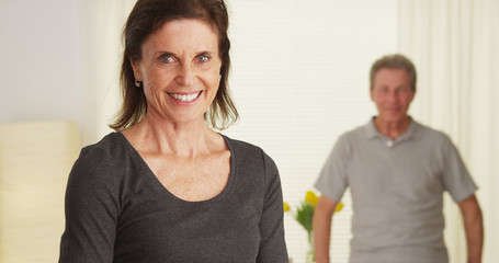 Senior couple standing in living room smiling