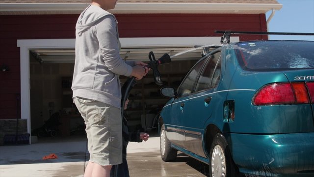 Mother washing car with her cute toddler