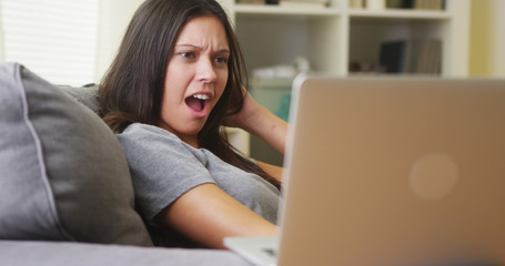 Mixed race woman watching horror show on laptop