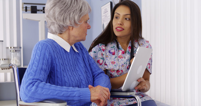 Hispanic Caregiver Talking With Tablet With Elderly Patient