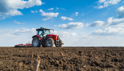 Obraz premium Farmer in tractor preparing land with seedbed cultivator