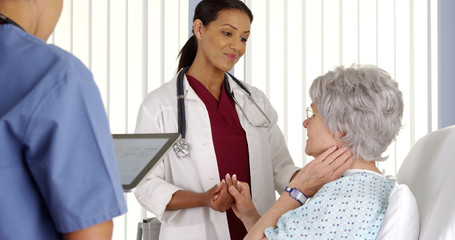 Obraz premium African American doctor consoling elderly woman patient in hospital bed