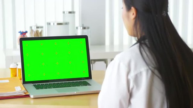 Chinese doctor talking to laptop with green screen