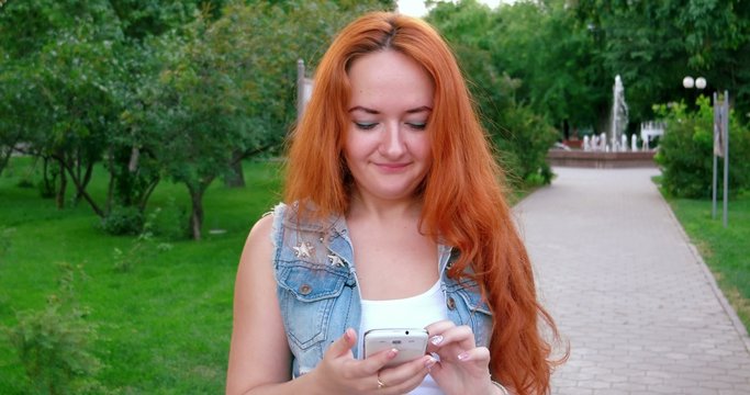 Redhead Texting on a smartphone. Women working with phablet