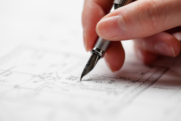 woman holding a pen over a house blueprint