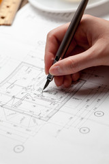woman holding a pen over a house blueprint