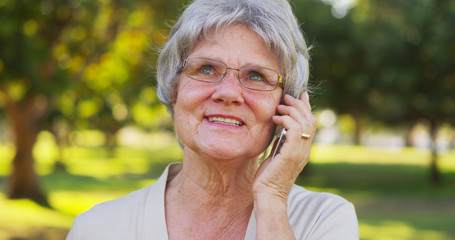 Senior woman talking on smartphone at the park