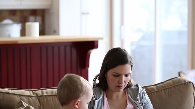 A Mother Nursing Her Boy While Toddler Plays On Ipad