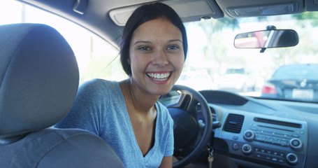 Happy mixed race woman sitting in car smiling