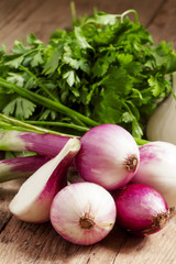 Fresh organic red onions with the stems on an old wooden table,
