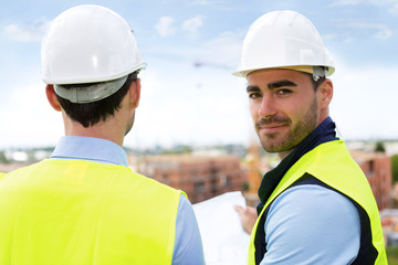 Engineer and worker watching blueprint on construction site
