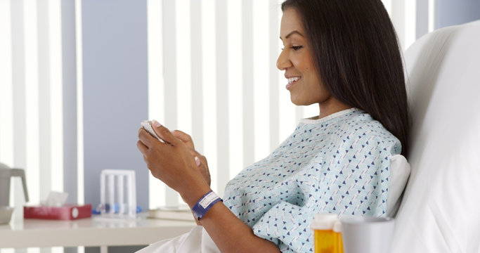 African American Woman Using Cell Phone In Hospital Bed