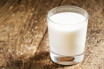 A glass of fresh milk on old wooden table, selective focus