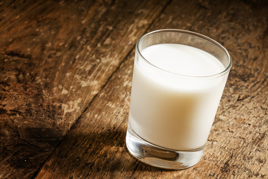 A glass of fresh milk on old wooden table, selective focus