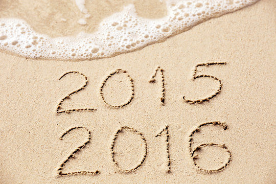 2015 2016 inscription written in the wet yellow beach sand being