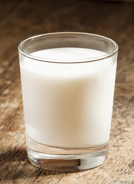 A glass of fresh milk on old wooden table, selective focus