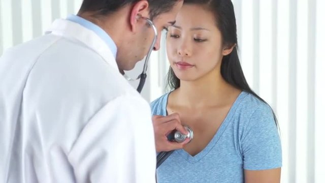Hispanic doctor listening to patient's heart