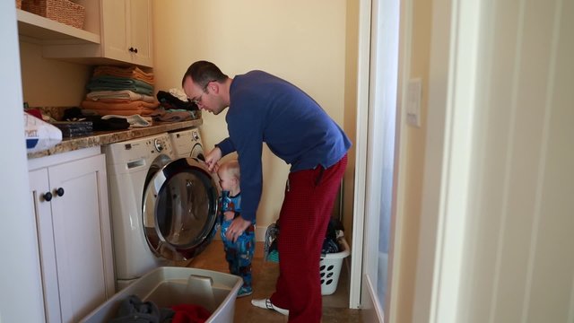 a single father doing laundry with his toddler