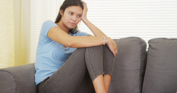 Mixed Race Woman Sitting On Couch Thinking