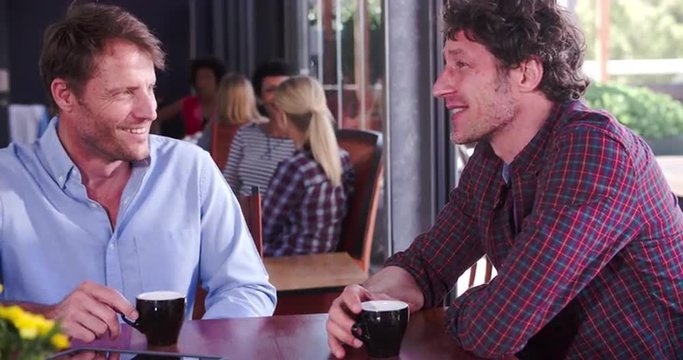 Two Mature Male Friends Sitting In Coffee Shop Chatting