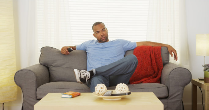 Black Man Sitting On Couch Watching Tv