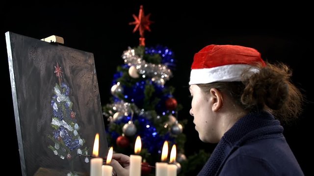 Female artist painting a real Christmas tree on canvas