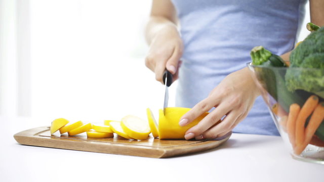close up of young woman chopping squash at home