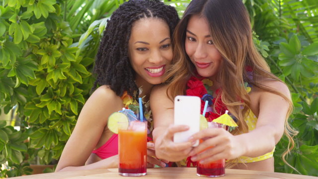 Black and Asian women taking selfie while on tropical vacation