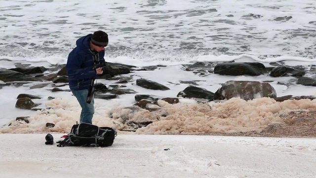 a photographer taking pictures of ocean in snowstorm