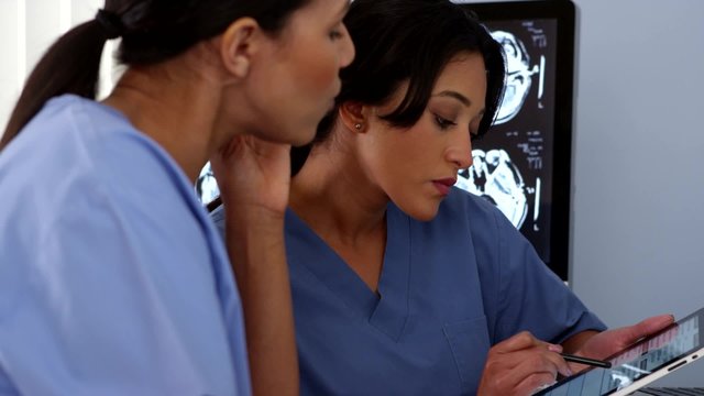 Close up of two female doctors using tablet and mobile phone