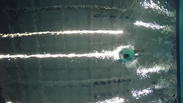 Slow motion of swimmer diving deep into pool underwater shot