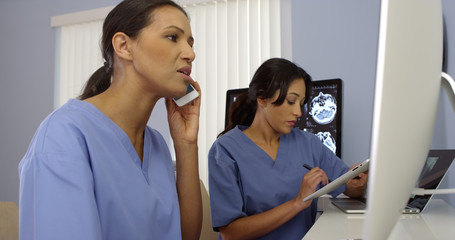 Two female medical personnel working as a team using modern technology