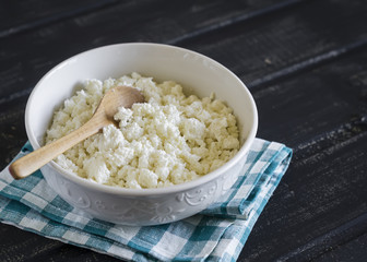 cottage cheese in a white bowl on a dark wooden background