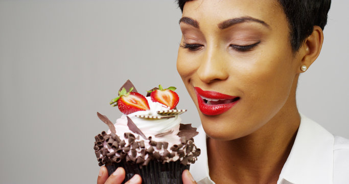 Woman admiring a fancy dessert cupcake with chocolate and strawberries