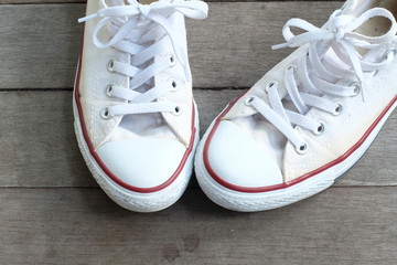 Fototapeta na wymiar Pair of white sneakers on wooden floor