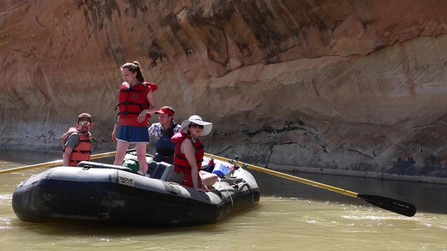 families rowing river rafts down san juan river by cliff