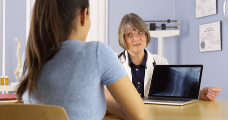 Senior doctor talking about xray to Hispanic woman patient